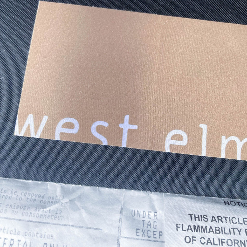 3. Detail of West Elm logo on a fabric tag attached to the sofa, representing the brand of the sectional.