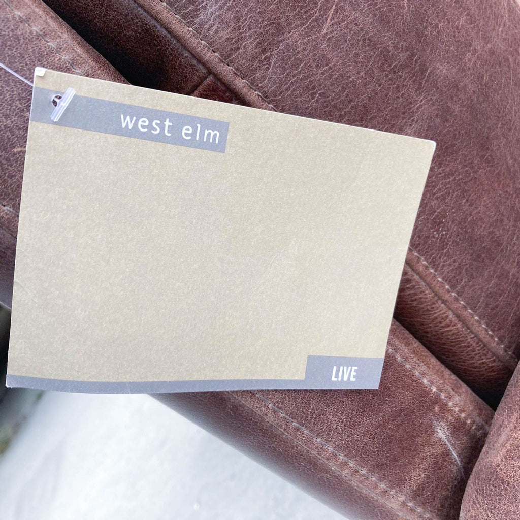 Brand tag on West Elm top grain leather sectional sofa, indicating the brand's name.