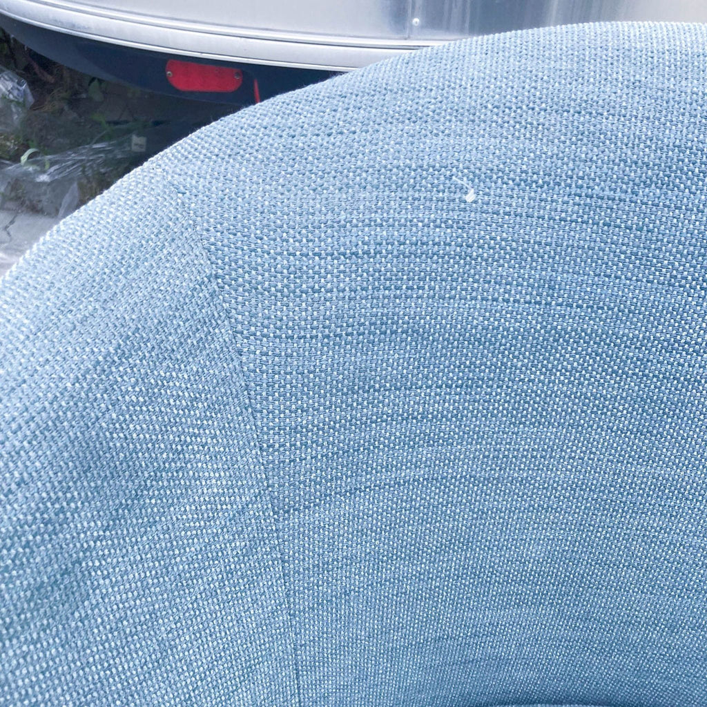 Detailed view of the backrest on the West Elm Crescent swivel lounge chair, featuring ocean blue woven upholstery.