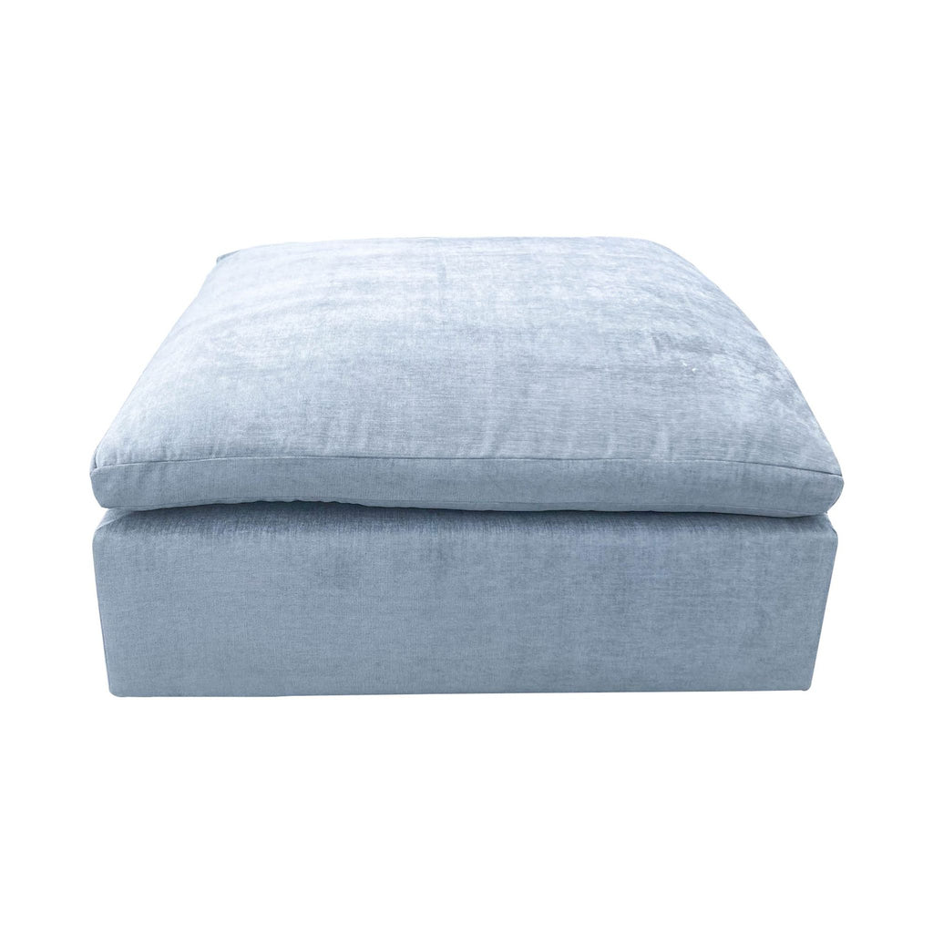 3. Elegant grey velvet ottoman by West Elm, displaying its plush cushion and sturdy design, doubling as a coffee table.