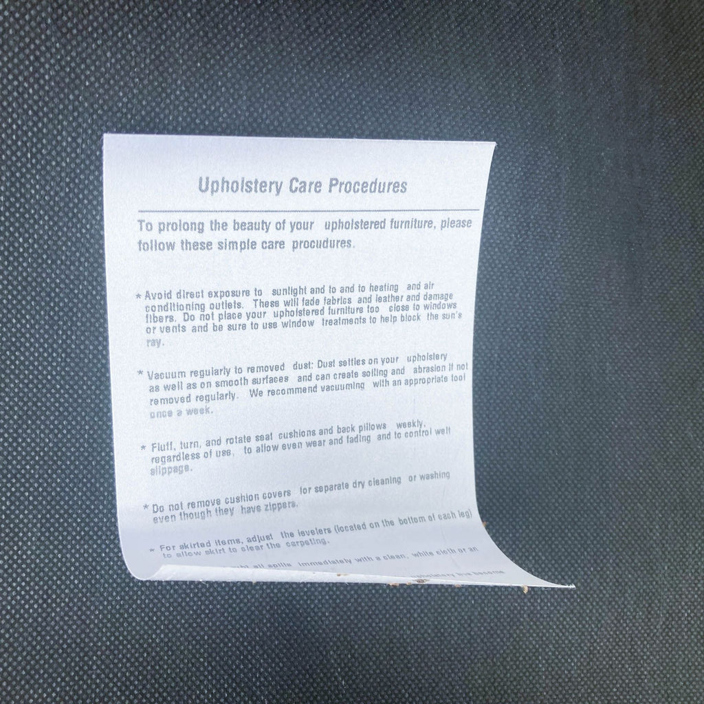 3. Care instructions for West Elm upholstered furniture shown on a paper against a textured surface.