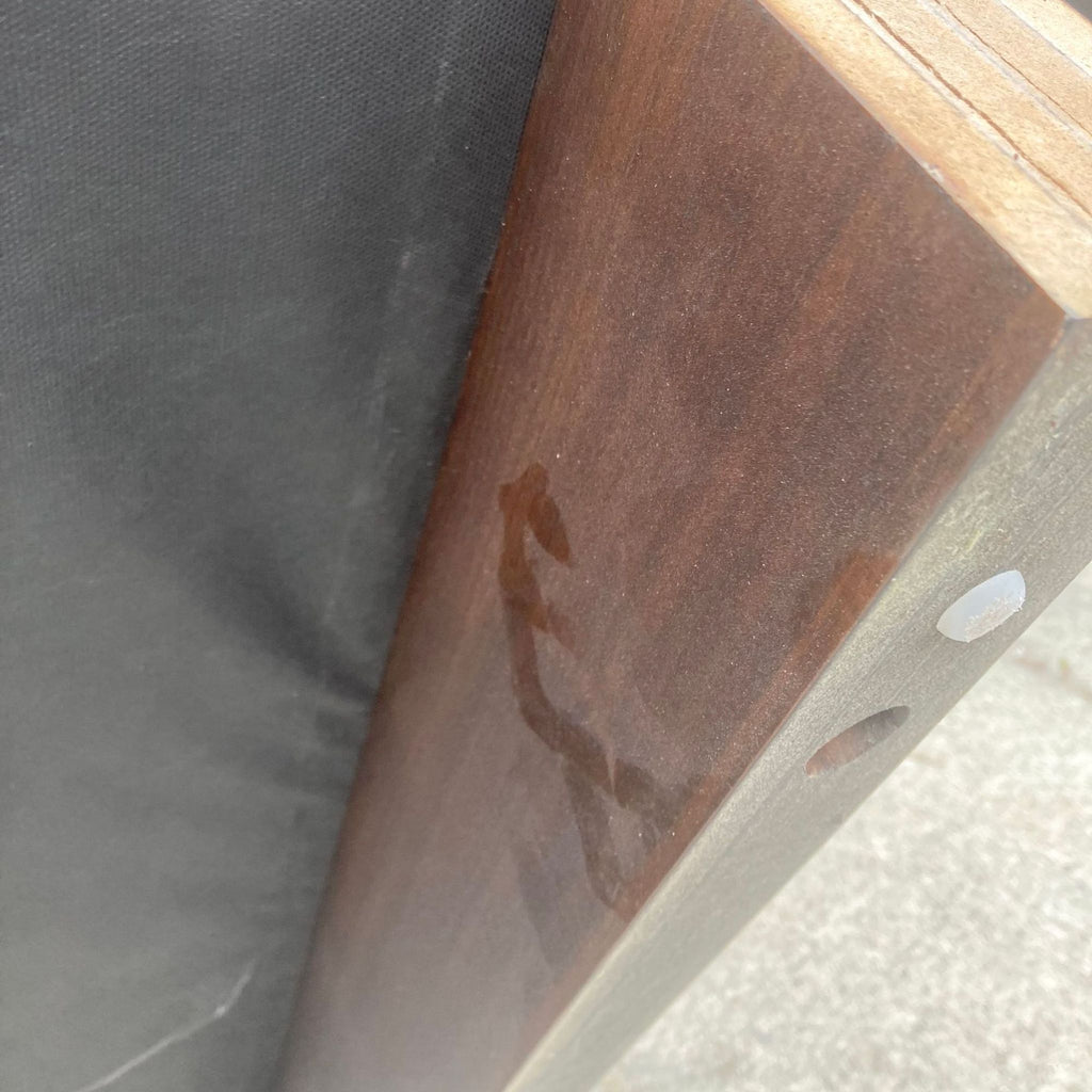 Alt text 3: Detailed view of a wood frame corner on a large, square ottoman or coffee table from West Elm, showing the texture and finish of the wood.
