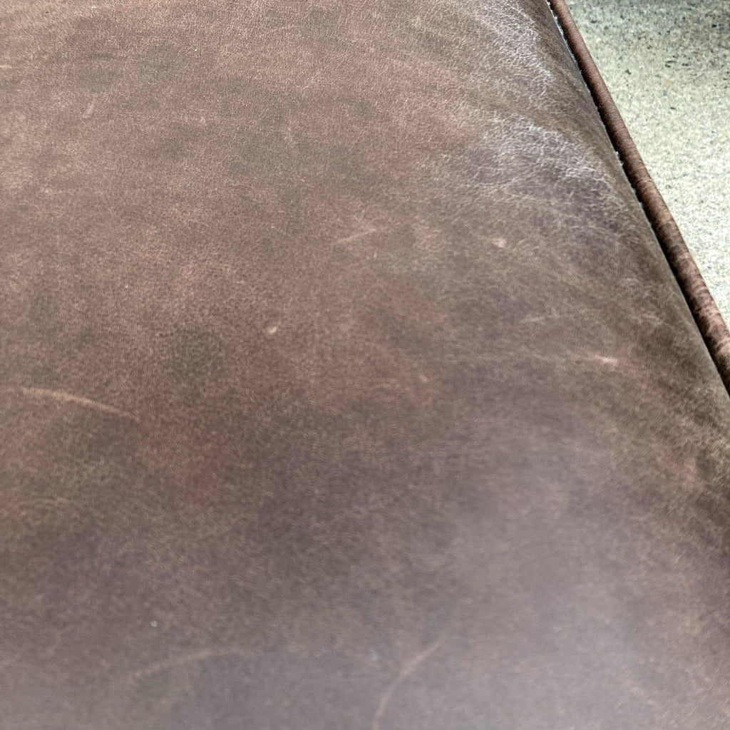 2. "Close-up of top grain leather texture on a Pottery Barn brown rectangular ottoman."