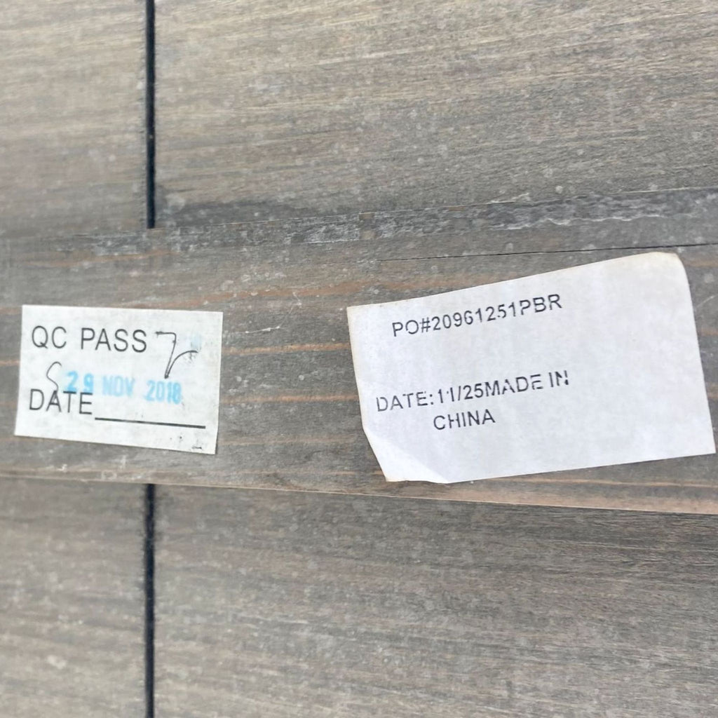 Quality control pass sticker and product details on a wooden surface indicating assembly date and origin.