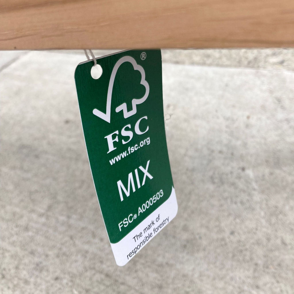 2. Close-up of a green Forest Stewardship Council (FSC) certification tag on a wooden Crate and Barrel furniture item.