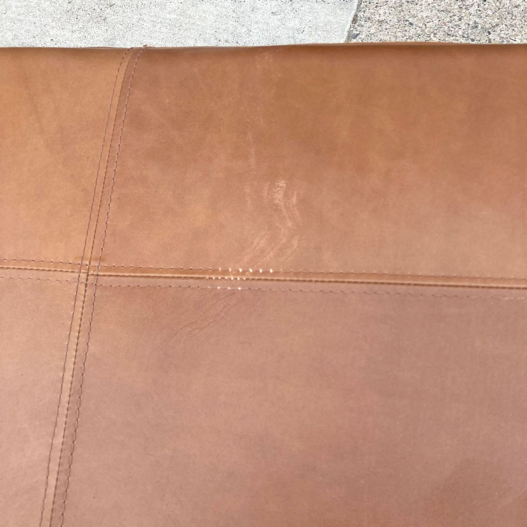 2. "Close-up of the stitched leather upholstery detailing on a West Elm bench."