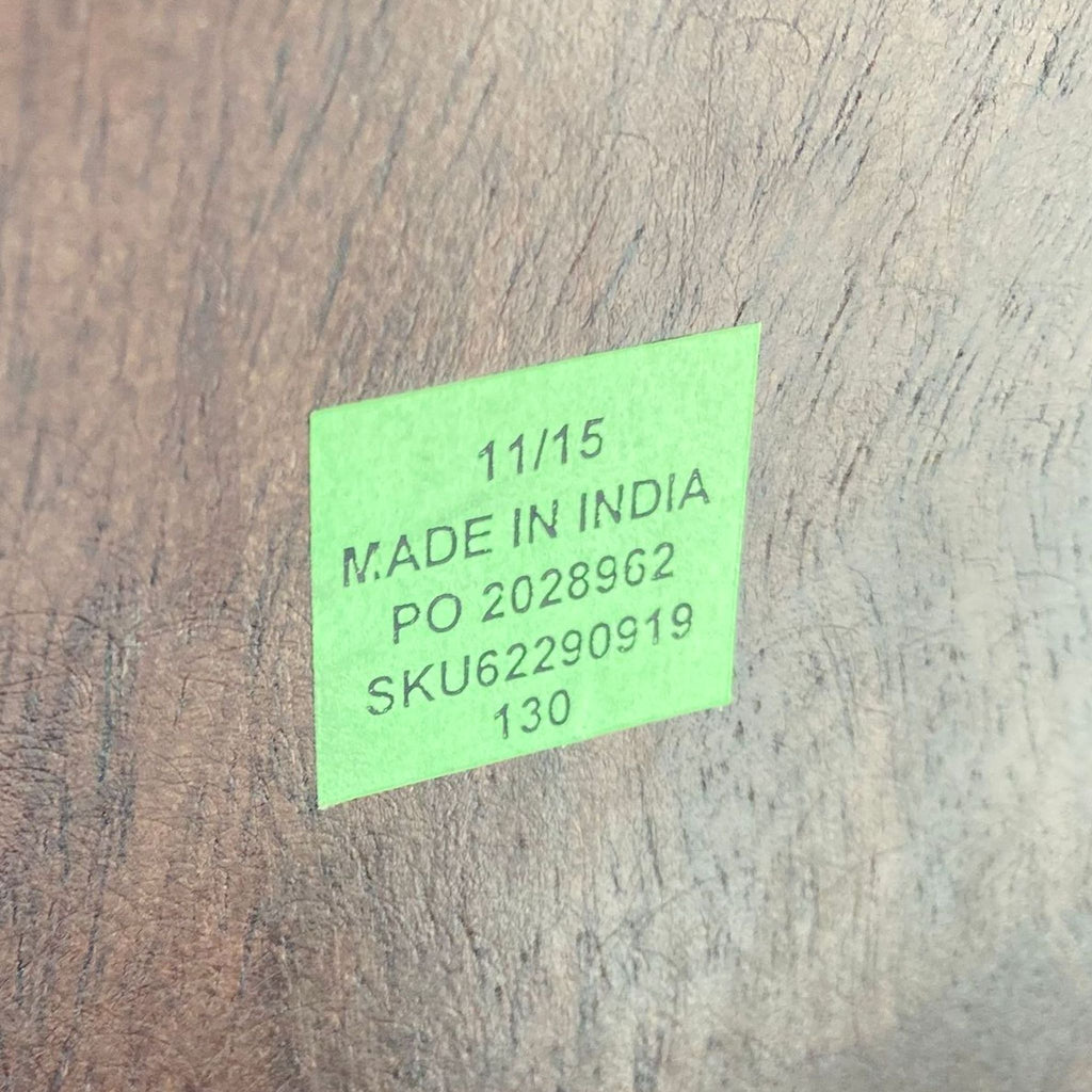3. Close-up of a manufacturer's green label on the wooden surface of a stool indicating "Made in India" and product information.
