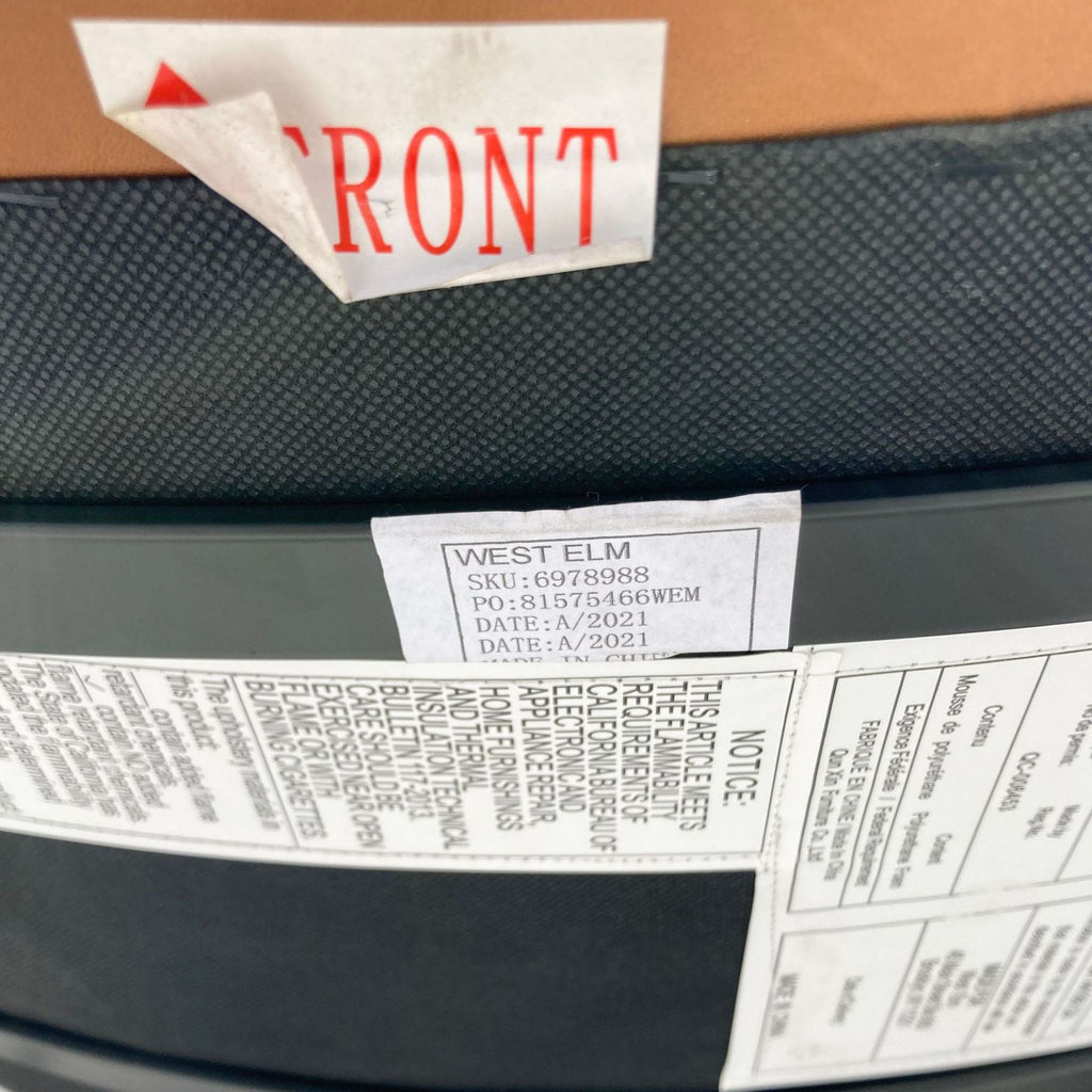 Close-up of a West Elm label on a saddle color barstool showing SKU and product information.