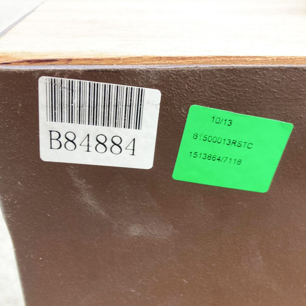 Close-up of a barcode label and green sticker with numbers on a brown surface of furniture.