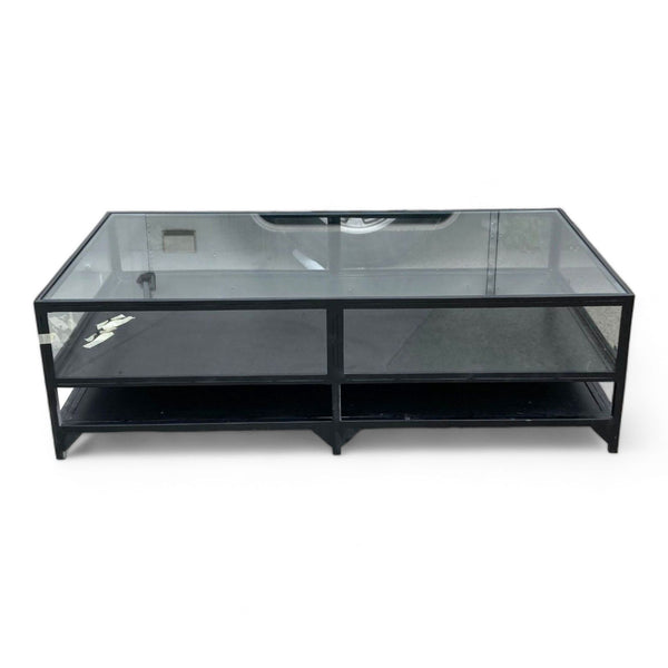 1. West Elm coffee table with a black metal frame and transparent glass surface showcasing two internal compartments.