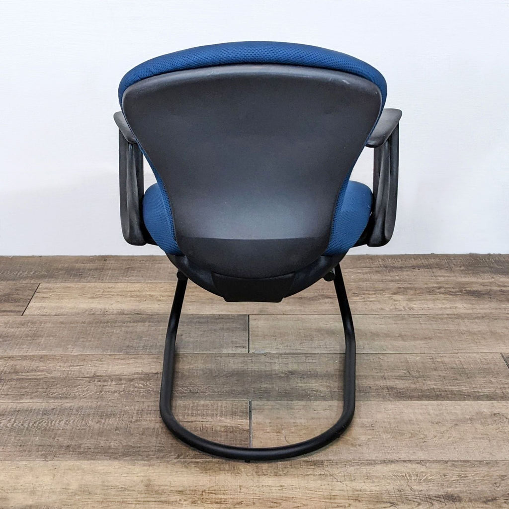 2. "Back view of a Reperch stackable blue and black office chair against wooden floor backdrop."