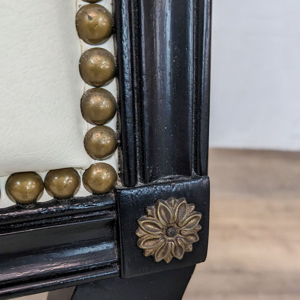 Close-up of a Hickory Chair Company lounge chair detailing the nailhead trim and gold gilded floral accent on a black lacquered frame.