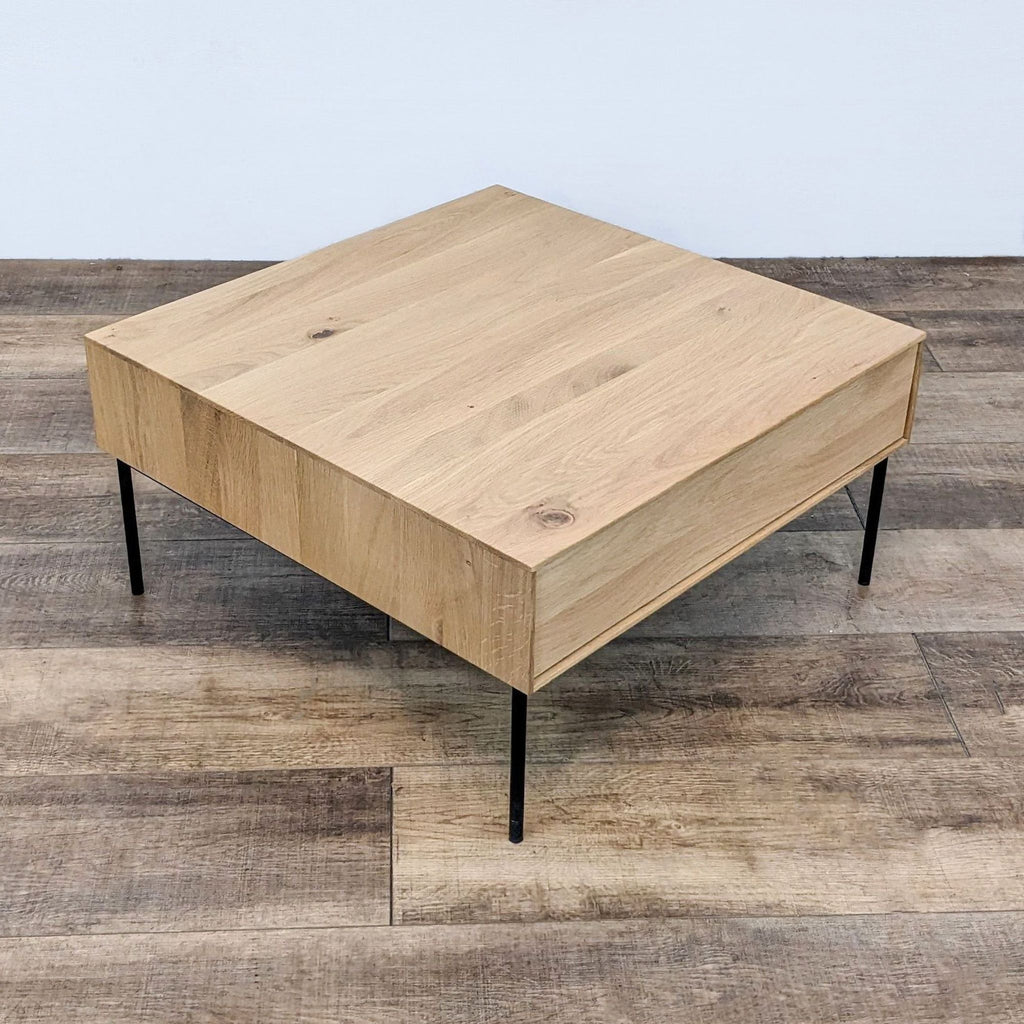 1. A square Industry West coffee table with a light wood finish and sleek black metal legs on a wooden floor.