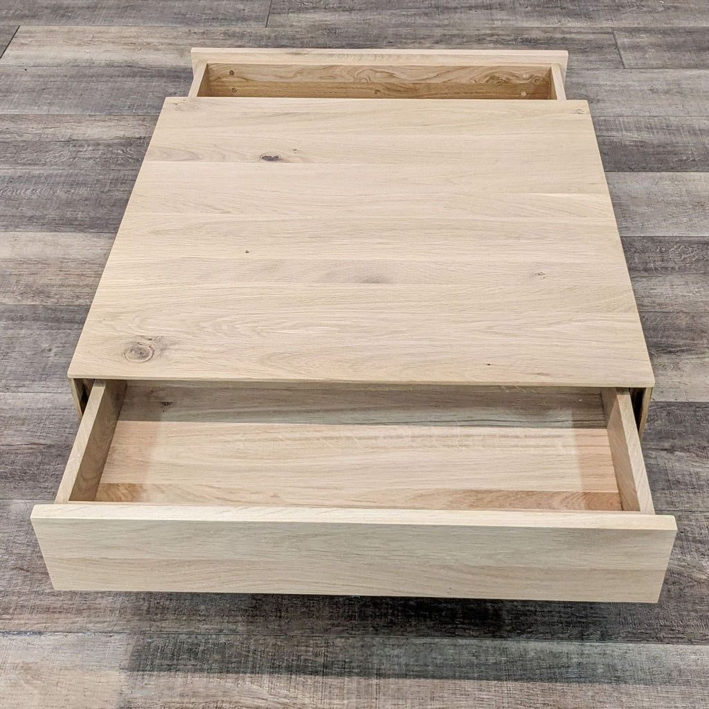 2. Open drawer view of a light wooden Industry West coffee table, showing storage capability, against a wooden floor background.