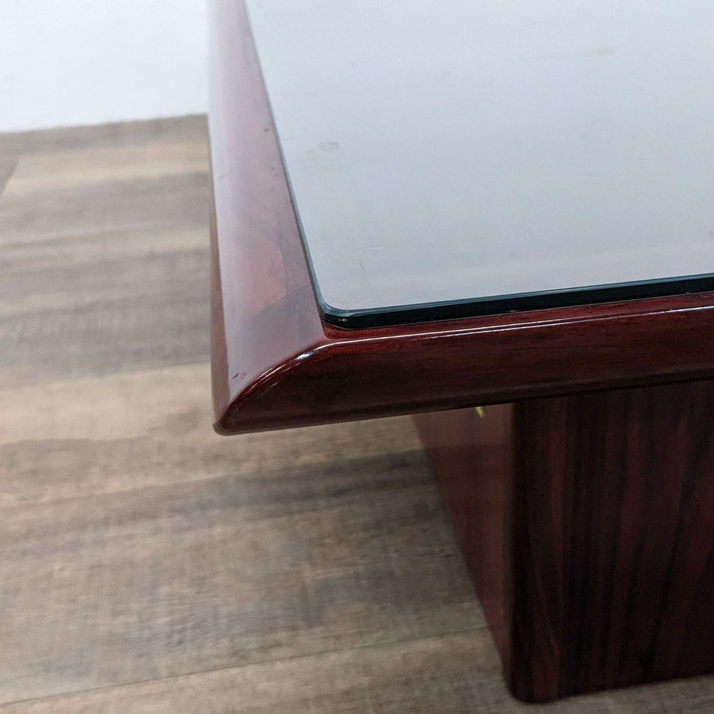 Close-up of the Reperch coffee table corner showing the glass top and the glossy wood finish.