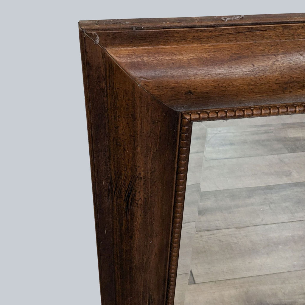 Close-up of dark walnut wood frame with beveled mirror detail.