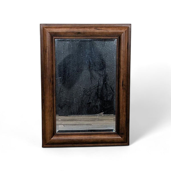 Beveled mirror with a dark walnut stained wood frame and trim details.