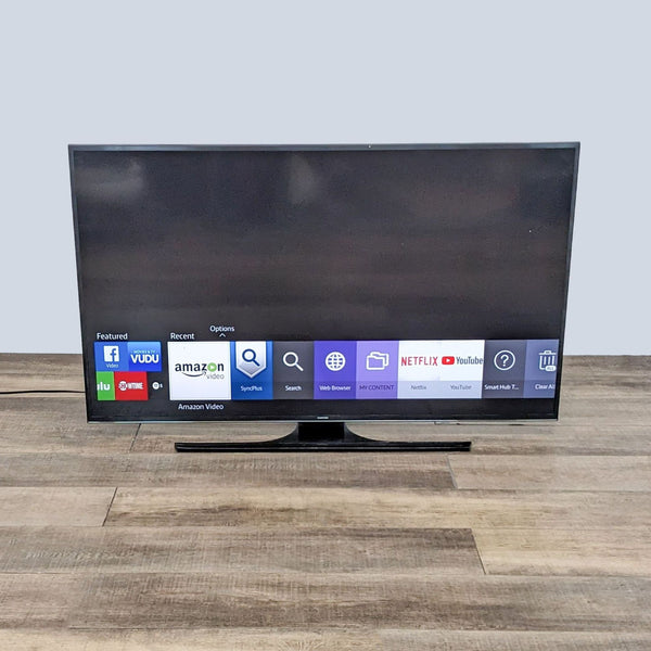 1. Samsung Smart TV on a wooden floor displaying streaming apps like Netflix and YouTube on its Full HD screen, showcasing built-in WiFi features.