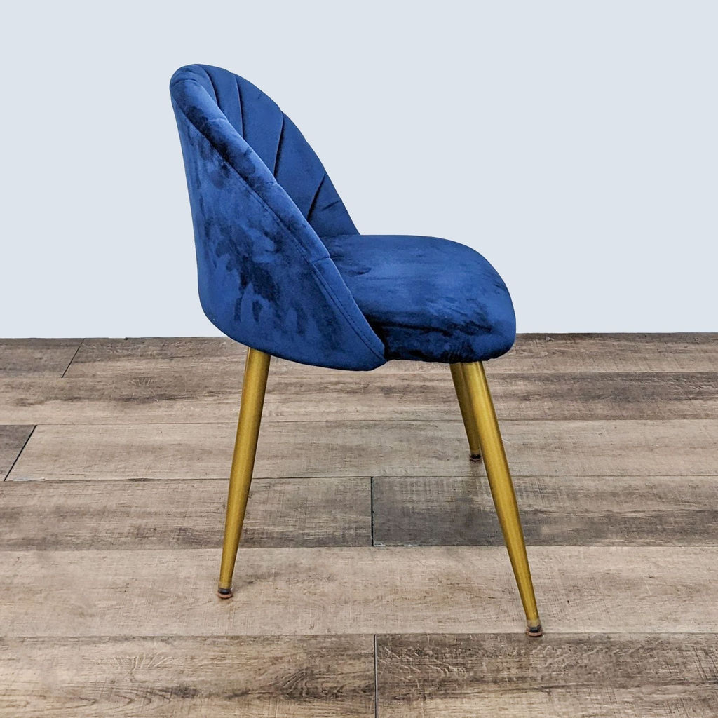 Side angle of a blue velvet Reperch dining chair with high-density foam and vertical tufting, showcasing gold metal legs.