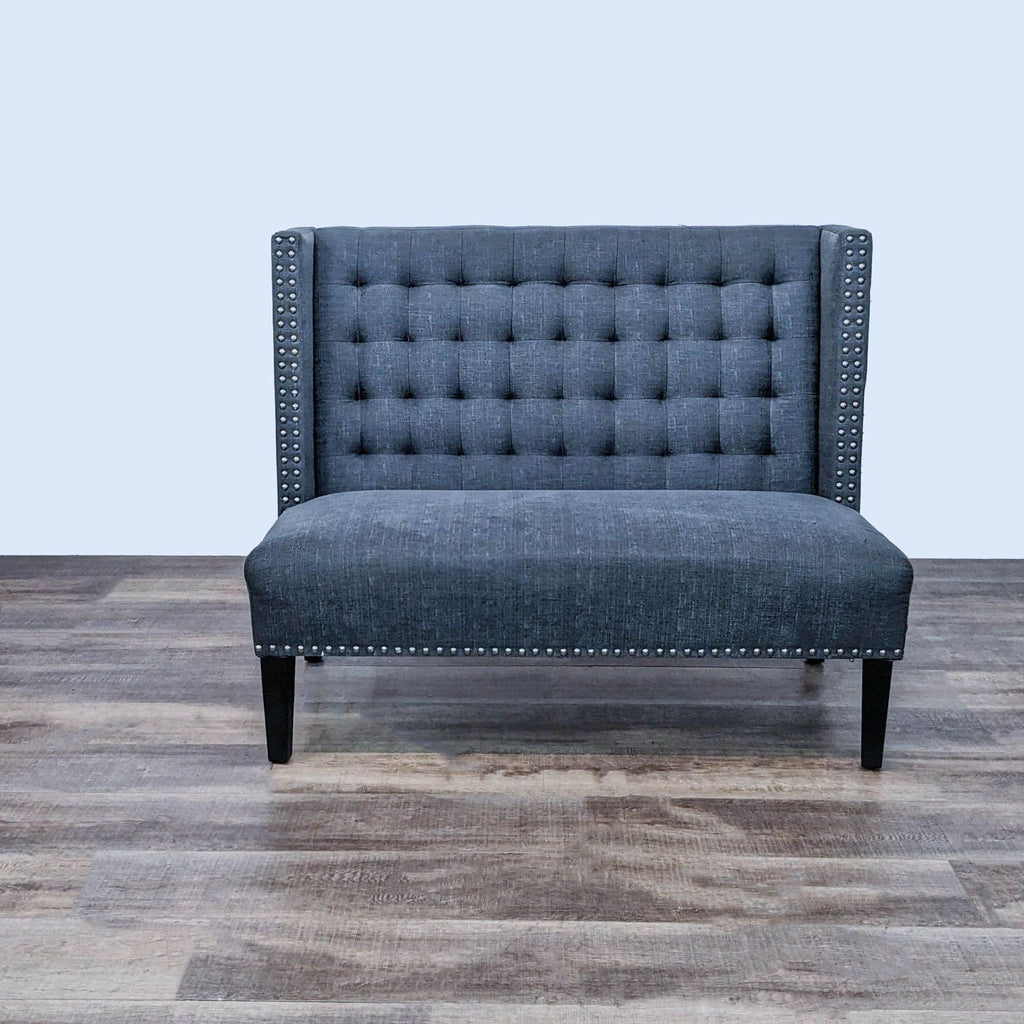 Dark grey tuxedo-style loveseat with high back and nailhead trim.