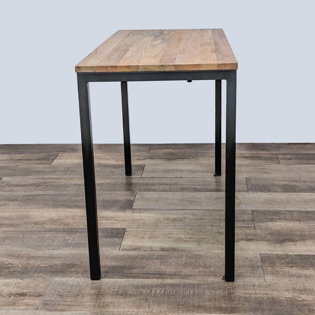 2. A modern dining table by West Elm featuring a warm, wooden tabletop with black metal legs on a wooden floor.