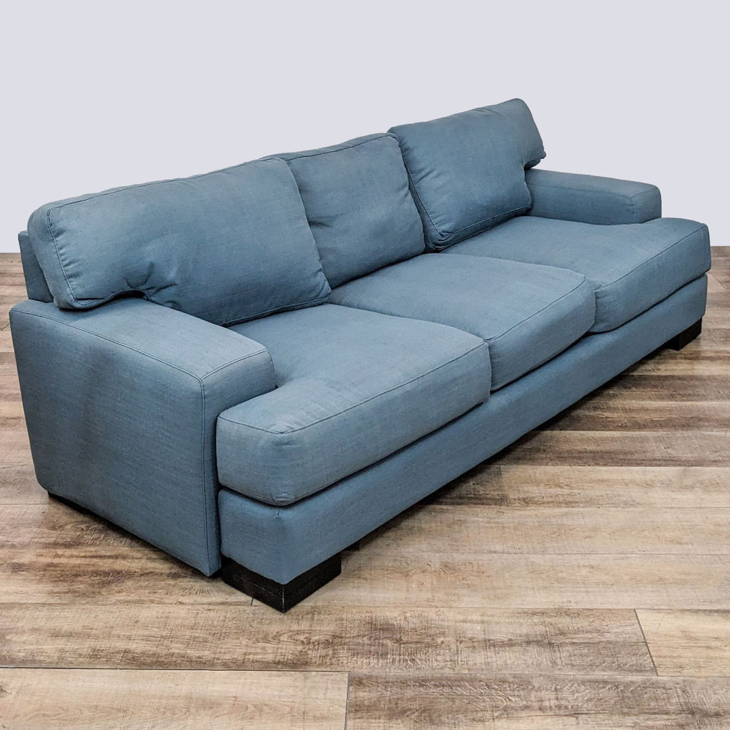 2. Three-seat sofa with blue upholstery, featuring block arms and dark finished wood feet, displayed in an interior setting with hardwood floors.