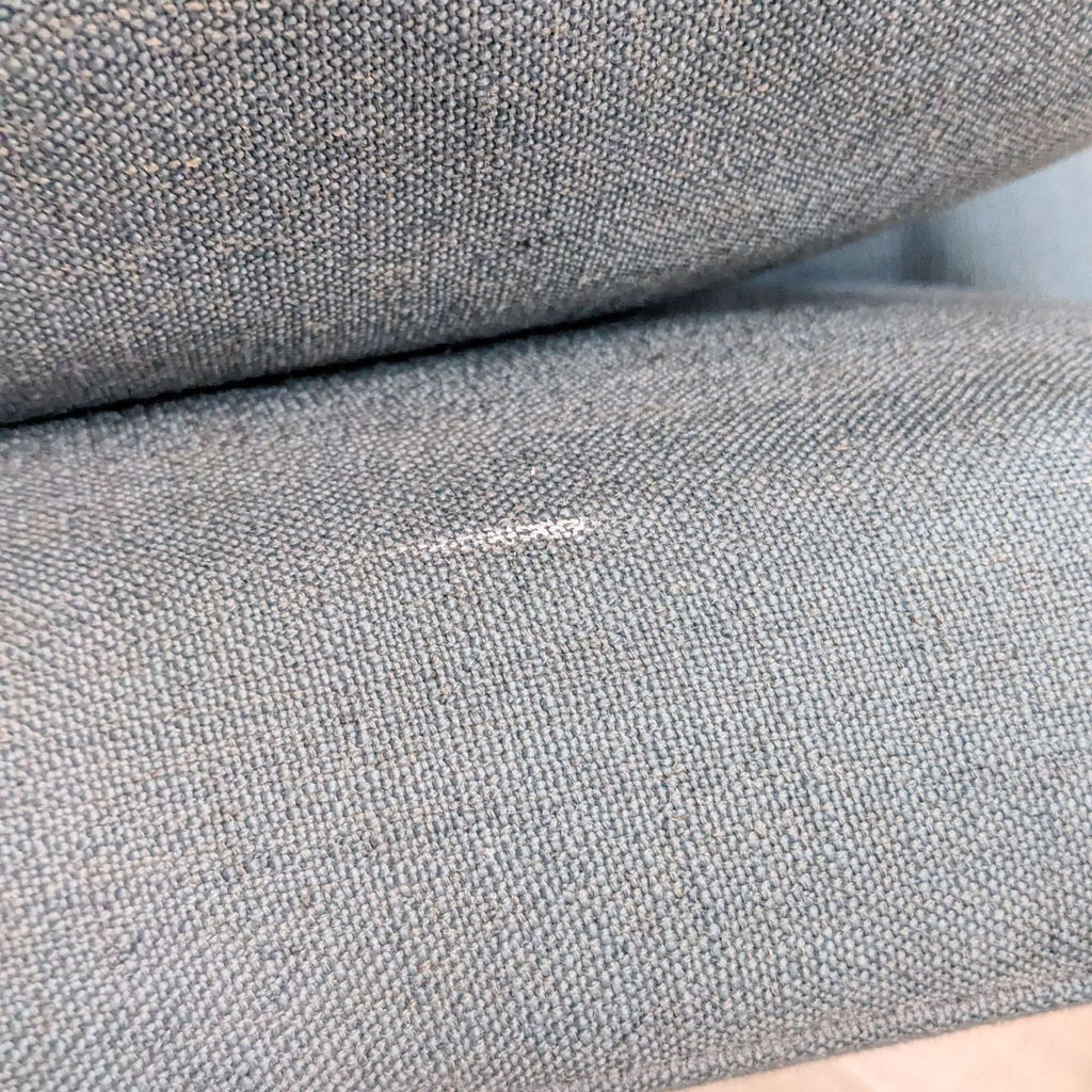 3. Close-up of blue slate fabric texture on an upholstered sofa highlighting the quality of the material with a visible seam.