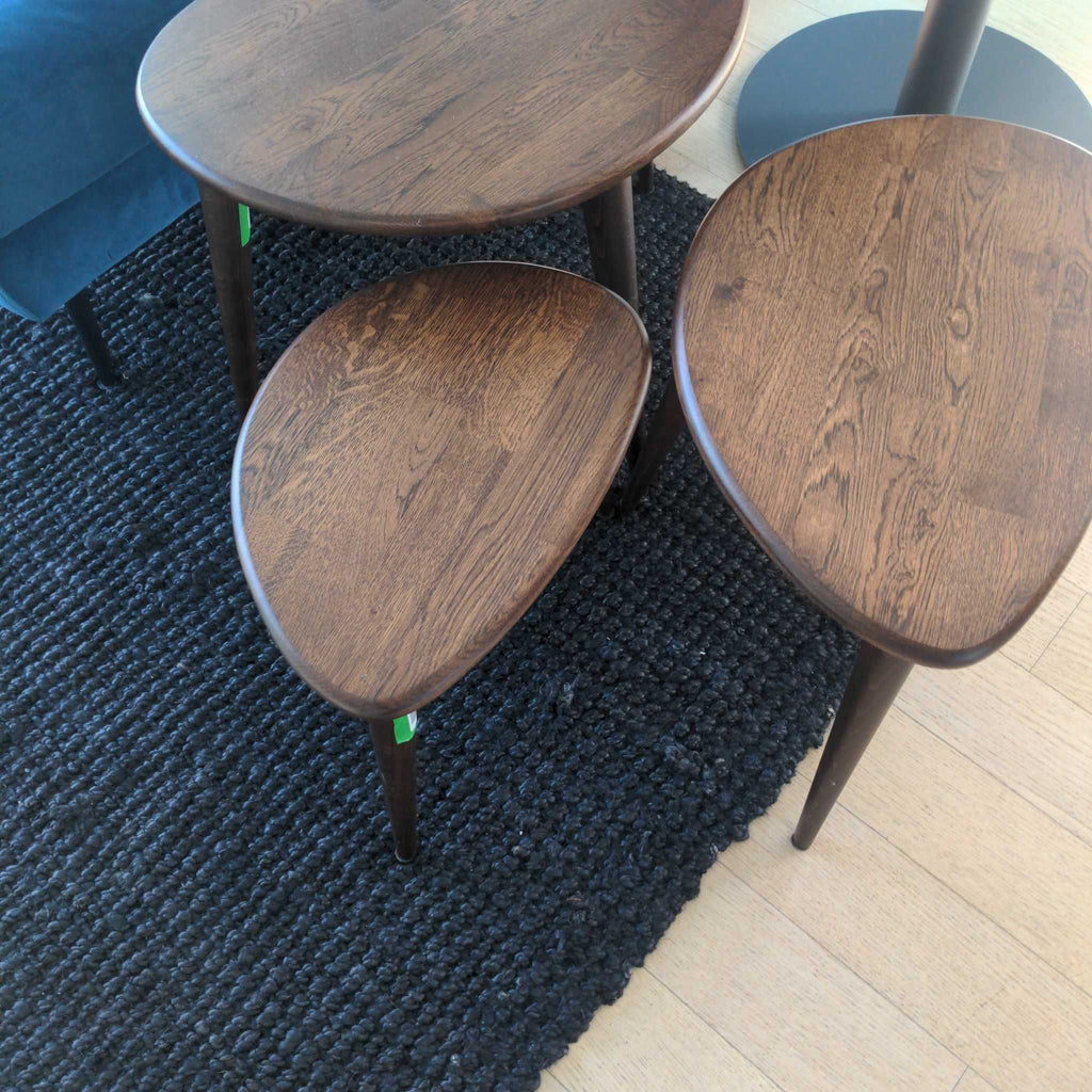 3. Set of dark wood side tables with tapered legs in good condition, displayed together on a black rug.