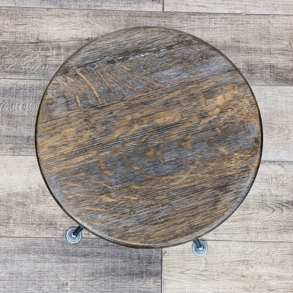 Top view of a round stool featuring a distressed wood finish and black metal base.
