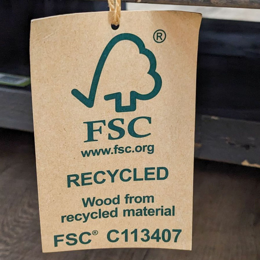FSC Recycled label hanging on a reclaimed pine wood coffee table from Living Spaces, indicating sustainable wood source.
