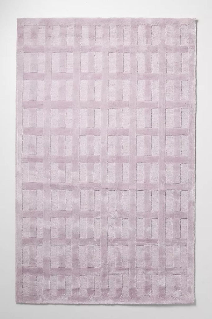 Alt text 1: Bella 8'x10' tufted lilac rug by Anthropologie with a geometric pattern displayed on a clean surface.
