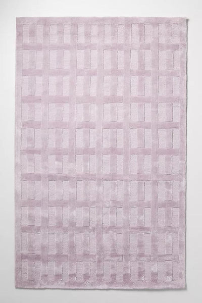 Alt text 1: Bella 8'x10' tufted lilac rug by Anthropologie with a geometric pattern displayed on a clean surface.