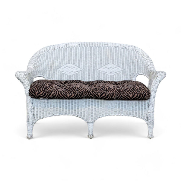 1. Classic white wicker loveseat by Reperch with tiger print cushions isolated on a white background.