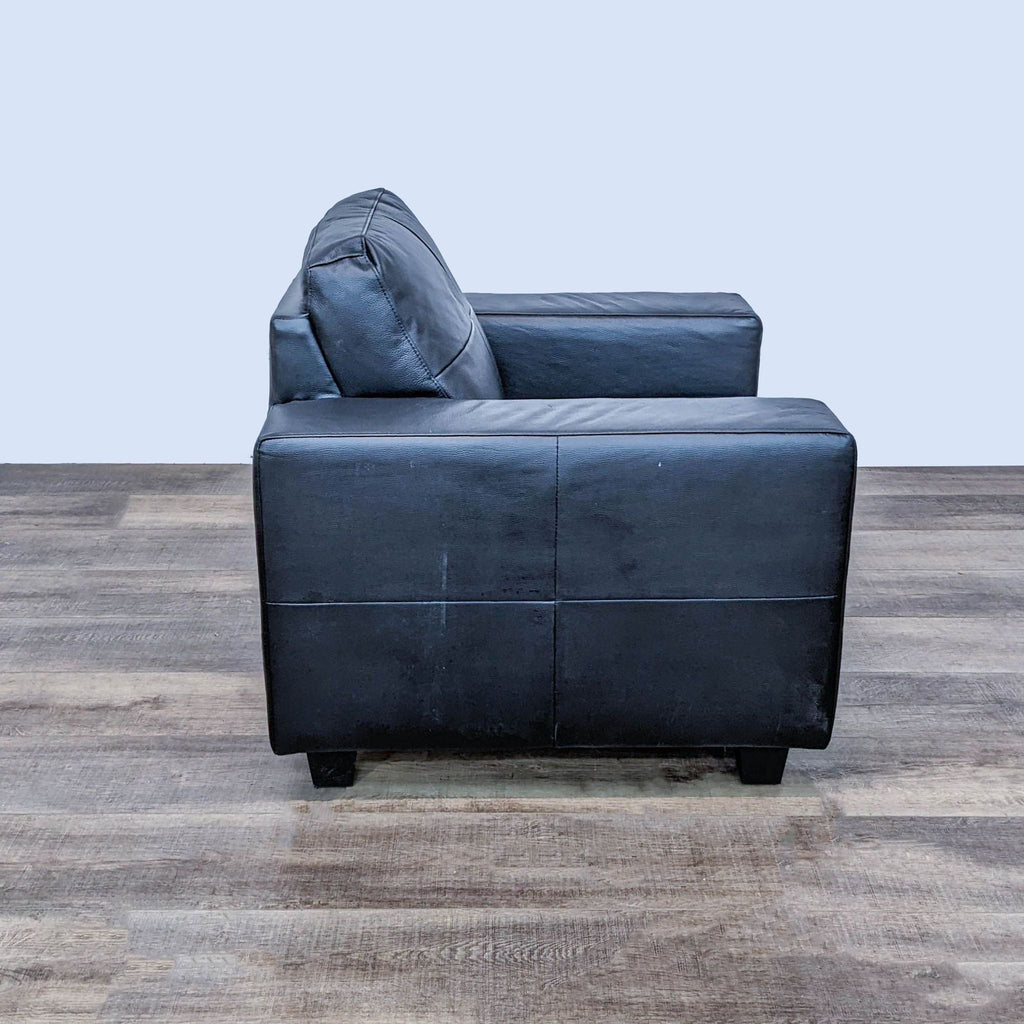 Side view of an IKEA Skogaby black faux leather club chair with wooden block feet.