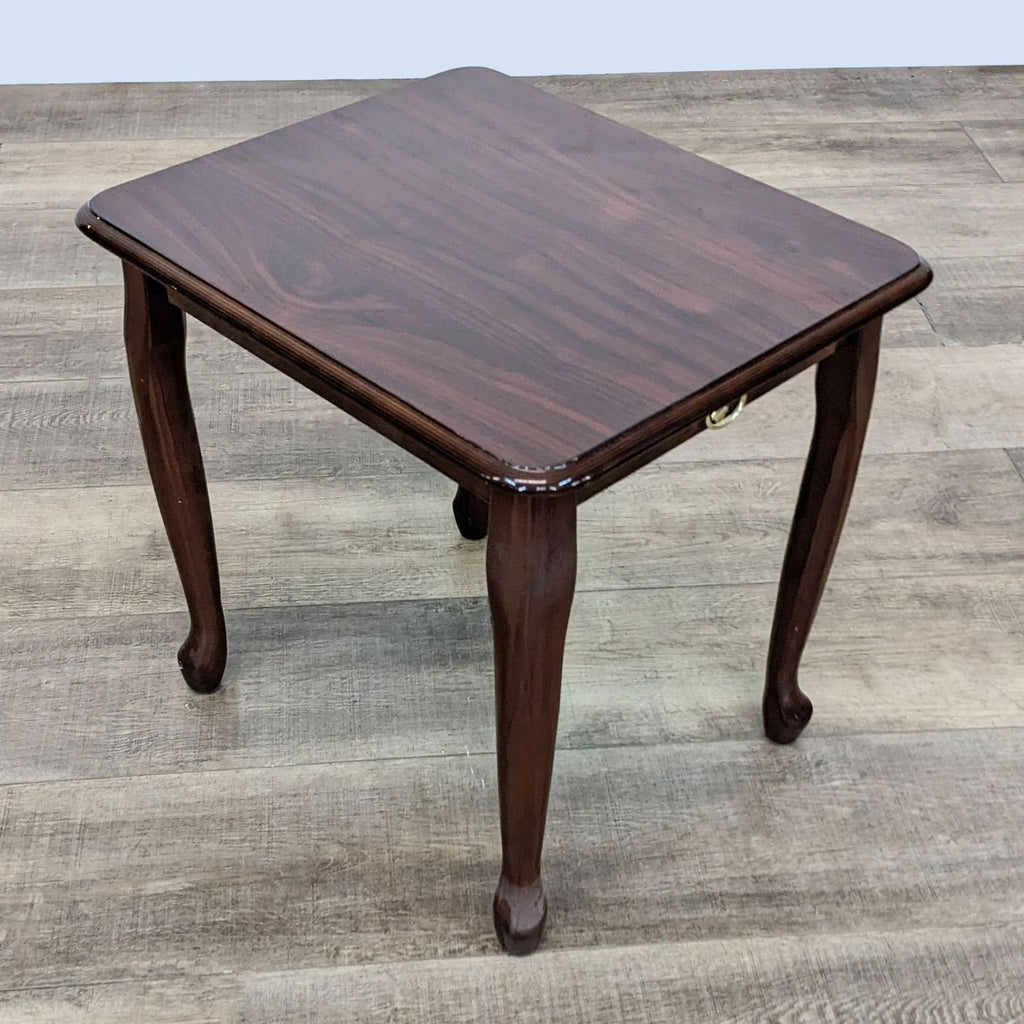Dark-stained Reperch end table featuring a decorative brass pull, elegant legs, and visible wood grain, viewed from an angle above.