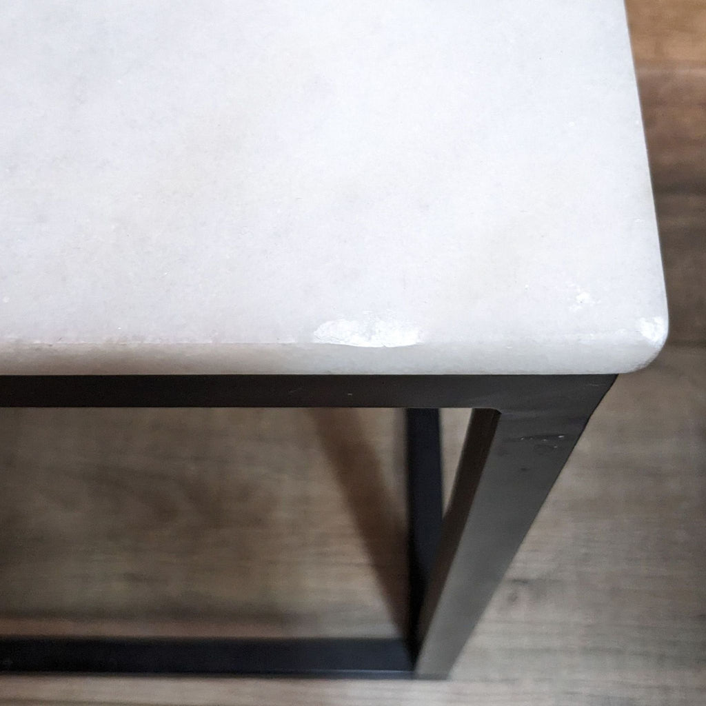 Close-up of the corner of Reperch table showing marble texture and metal frame.