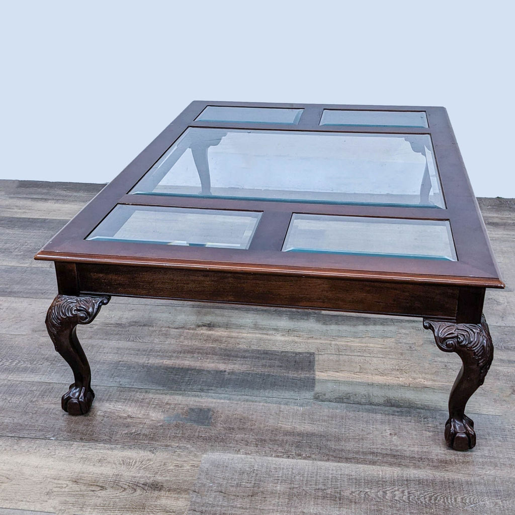 Elegant Reperch coffee table with beveled glass sections and ornately carved wooden legs on laminate.