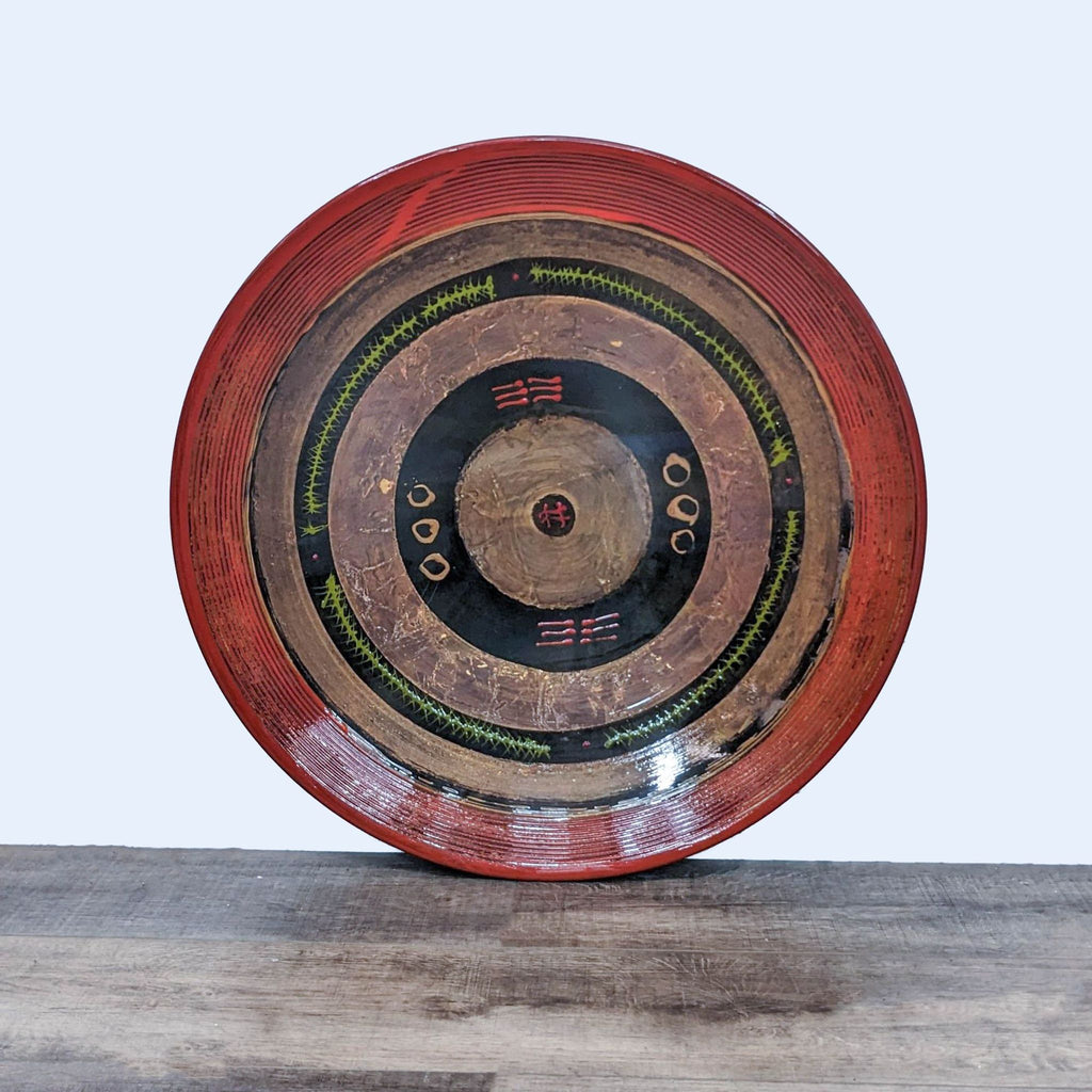 1. Hand painted Reperch wall art plate with concentric patterns in red, green, and black on wooden surface.