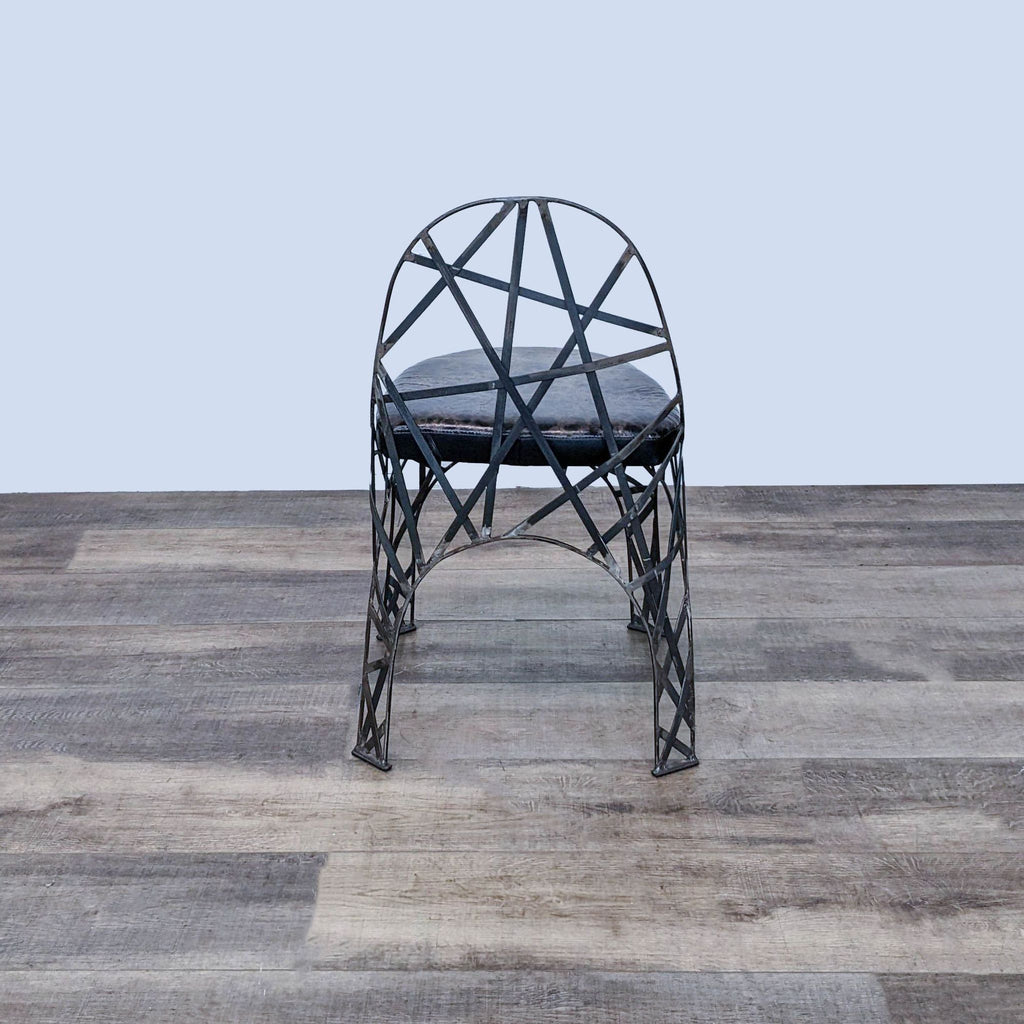 Reperch abstract metal stool featuring a unique mottled leather seat, displayed on a wood-patterned floor.