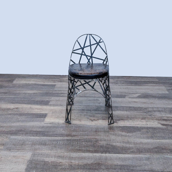 Metal stool with geometric design and mottled leather seat by Reperch, on wooden floor.