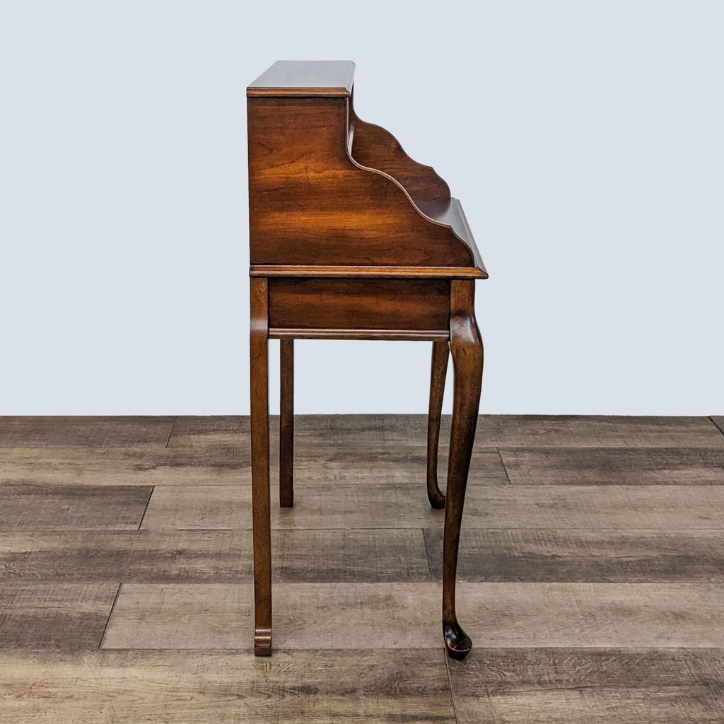 Side profile of wooden Ethan Allen desk highlighting its curved design.