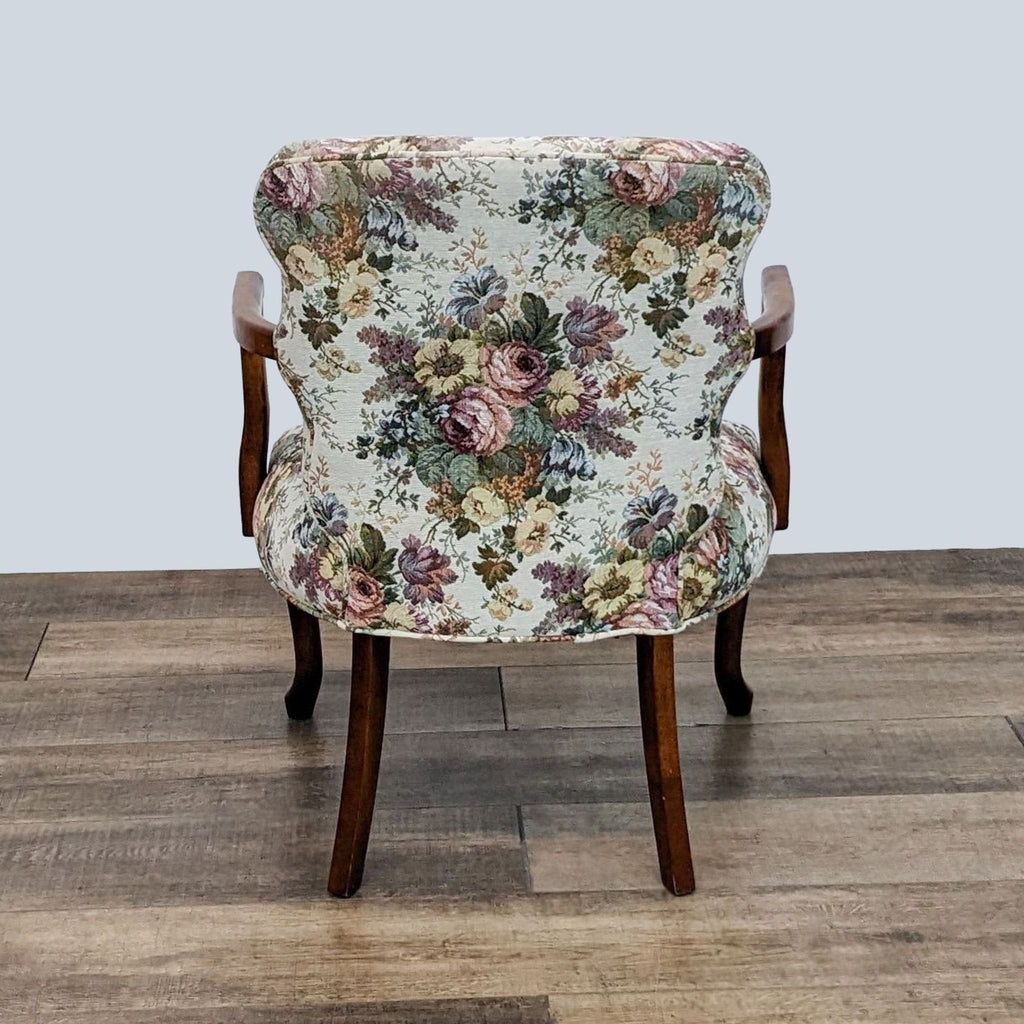 2. Rear view of an Ethan Allen armchair with floral upholstery and wooden queen anne style legs on a wood floor.