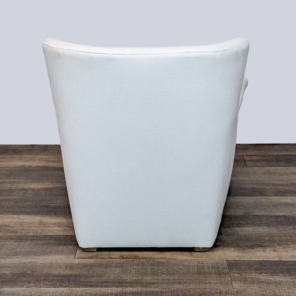 Rear view of a minimalistic white Reperch lounge chair against a wooden floor background, displaying its clean lines.