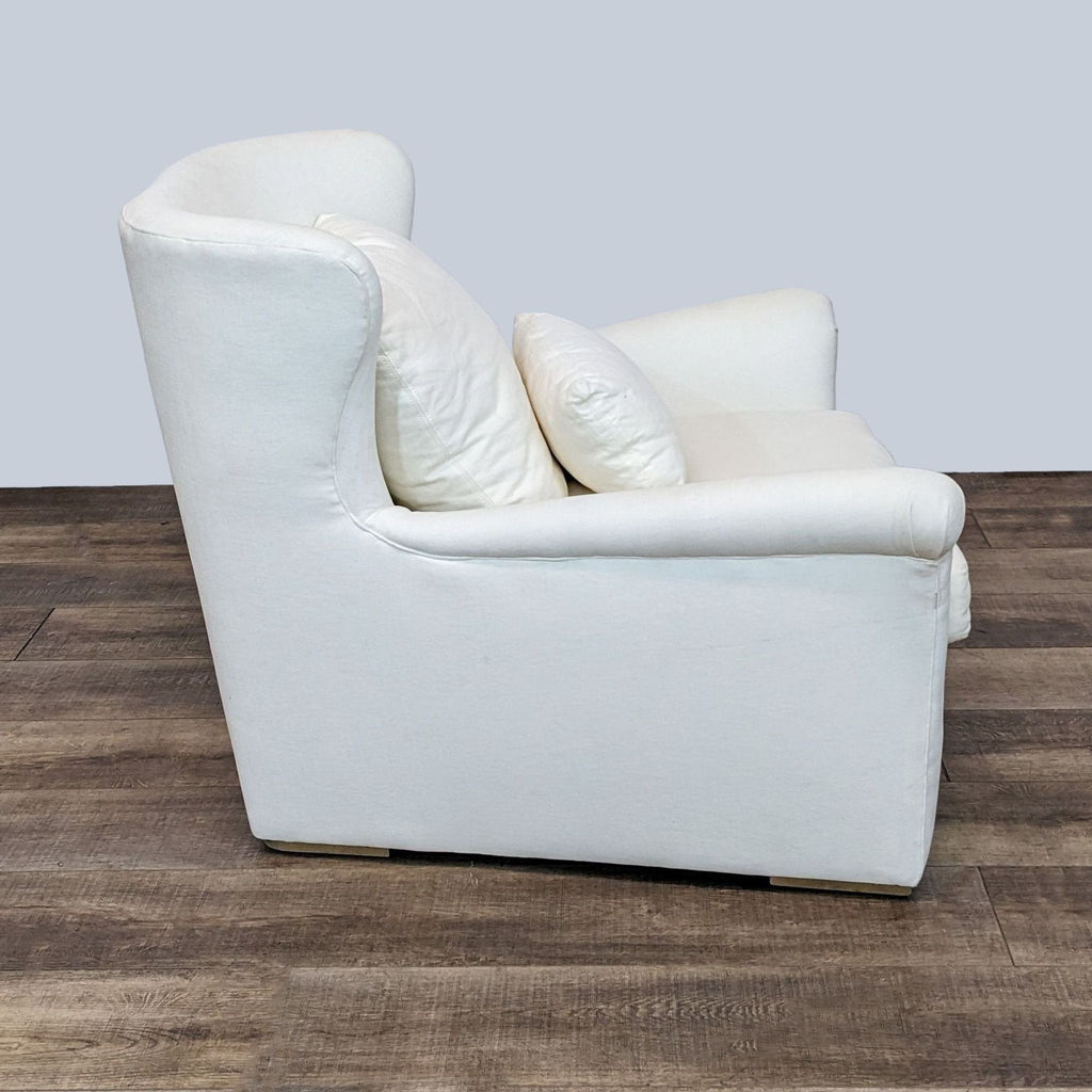 Side view of a white Reperch lounge chair showcasing its sleek design and comfortable cushioning on wood floor.