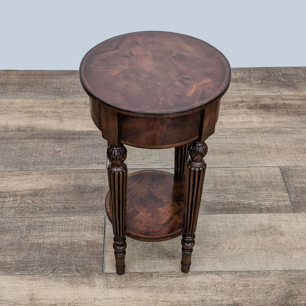 Reperch inlaid round table with detailed carved legs on a wooden floor.