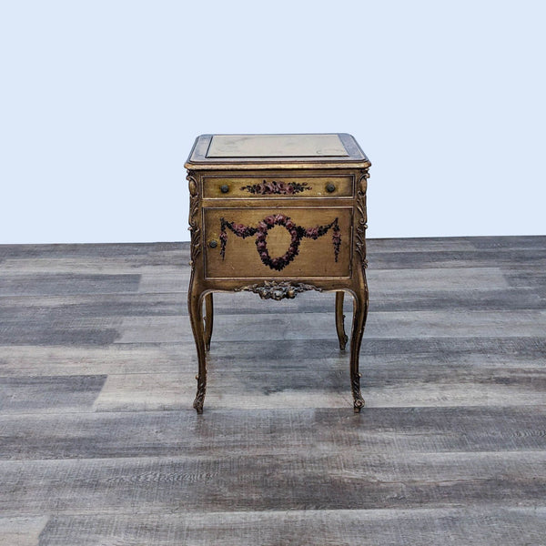 Reperch brand end table with carved floral designs, single drawer, and gold mirror top on a wooden floor.