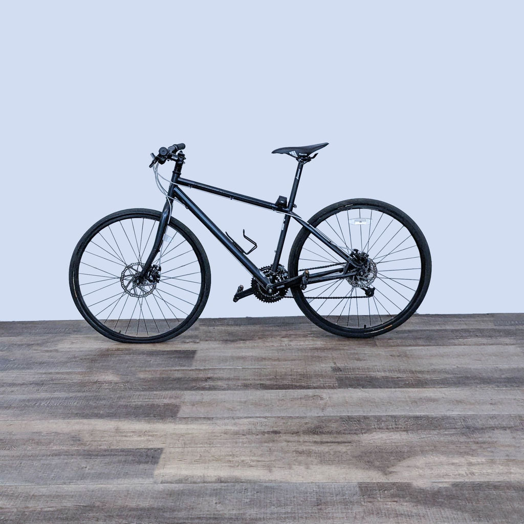 Versatile black Reperch bike with sturdy frame, positioned on wooden floor against a plain background.