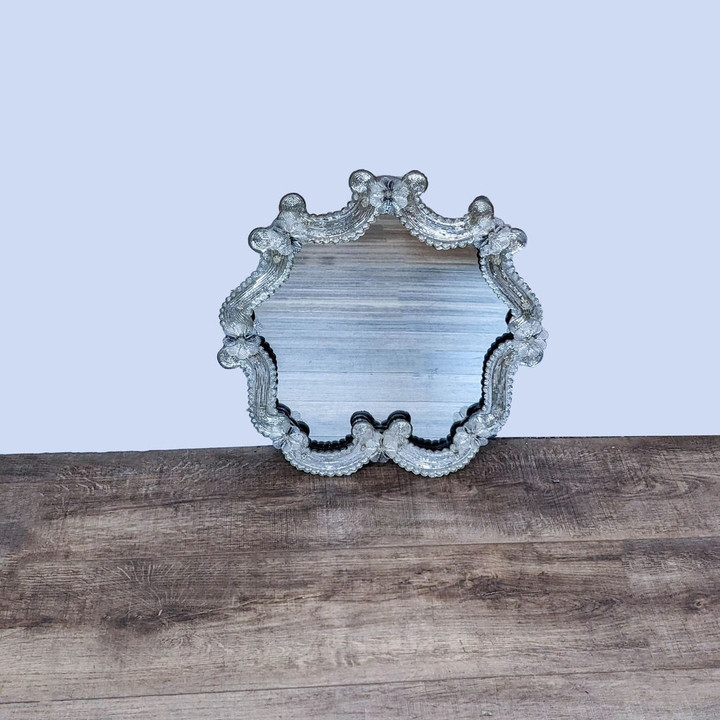 Murano art glass mirror by Reperch with scalloped edges and flower motifs on a wooden surface.