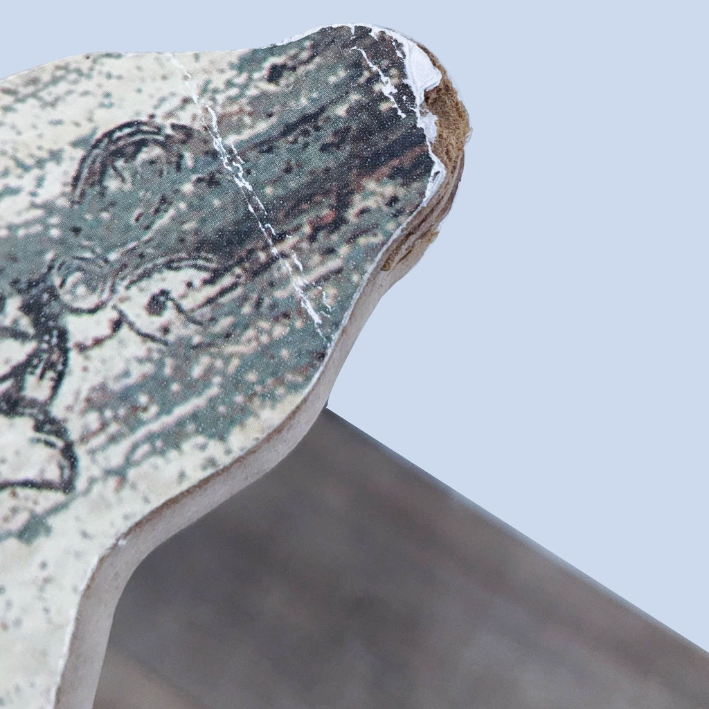 Weathered edge of the Peacock Park mirror frame, showing artistic texture.