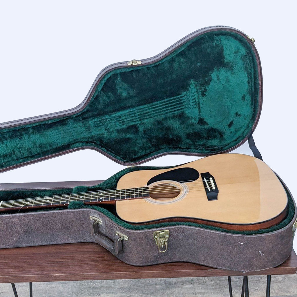 Open durable guitar case on a table with a Takamine acoustic guitar partially inside it.